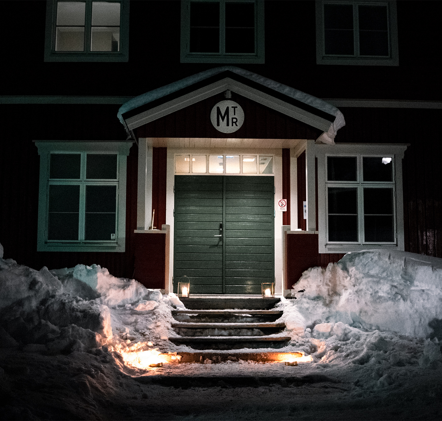 Meteorologens entré omgiven av snövallar, upplyst med marschaller och